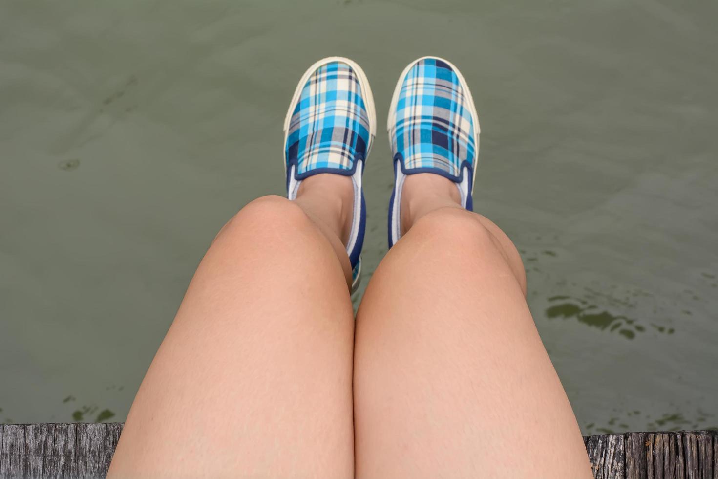 Canvas sneakers on feet on the wooden bridge photo