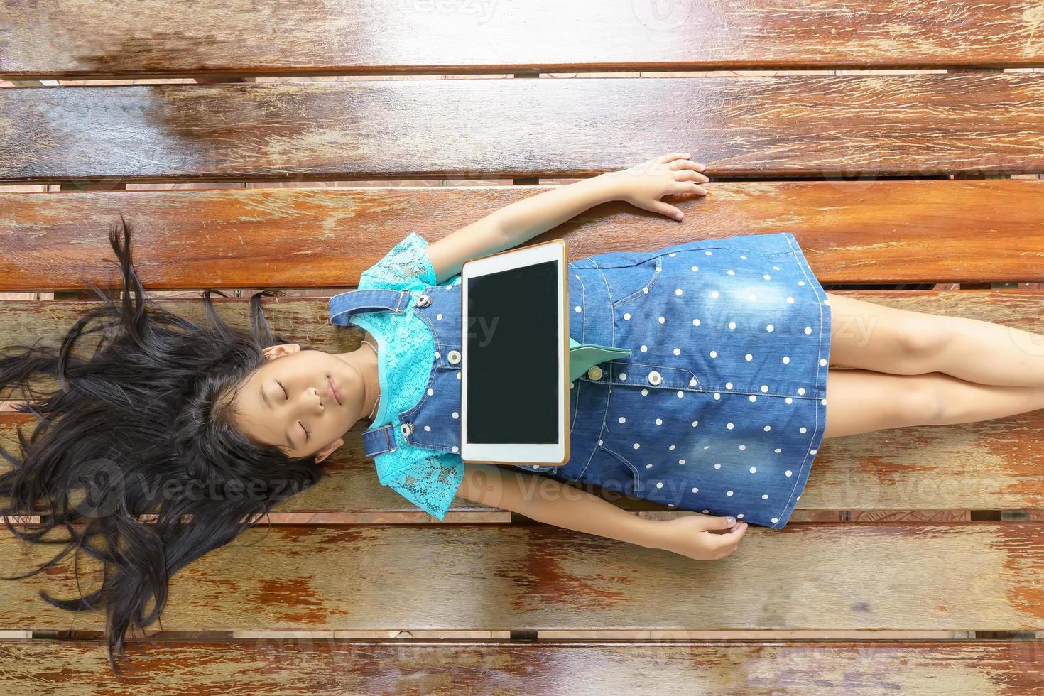 The girl sleep while playing tablet on wood beds. photo