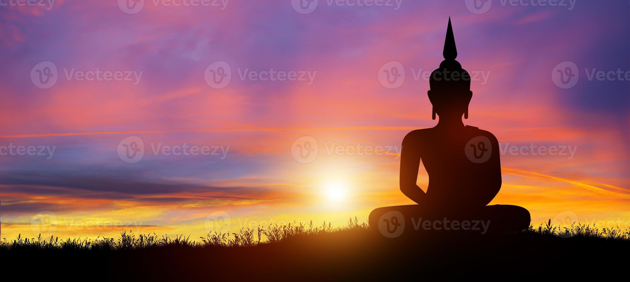 Silhouette of Buddha mediating in the twilight with sunrise background. Buddhist holiday Concept. photo