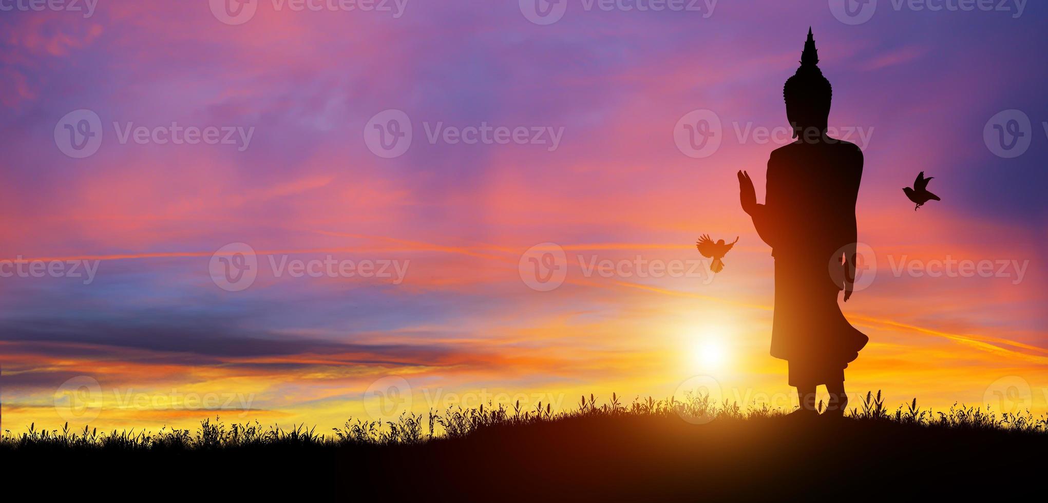 Silhouette of Buddha mediating in the twilight with sunrise background. Buddhist holiday Concept. photo