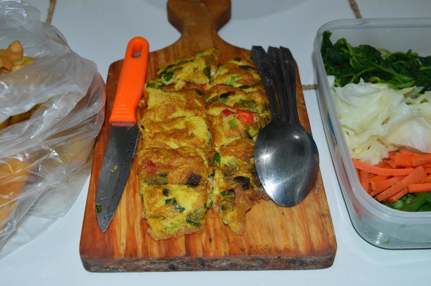 omelette on a wooden tray and vegetables to make pecel photo