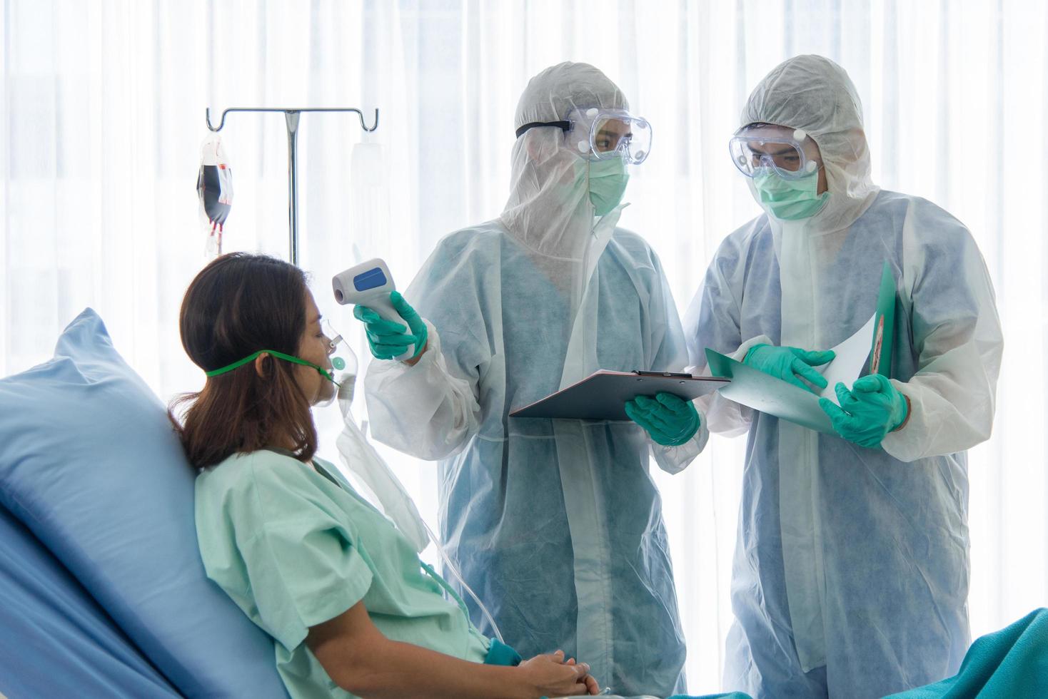 los médicos con traje protector están monitoreando y revisando al paciente infectado con corona visrus o temperatura covid-19 en la sala de cuarentena del hospital foto