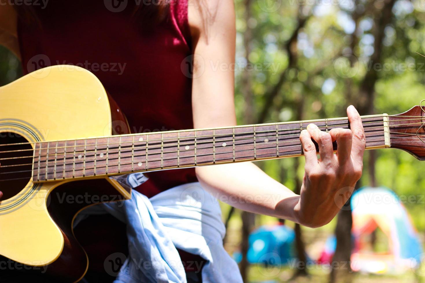 The hand of girl playing the guitar during her camping photo