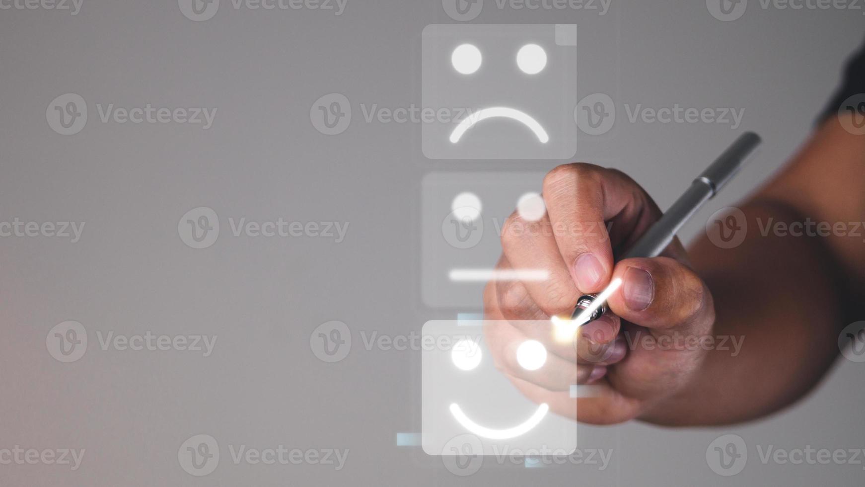 Evaluation and satisfaction concept. Someone chooses a smile emotion that is an excellent review with digital pen. Medium close up shot is on grey background with copy space. photo