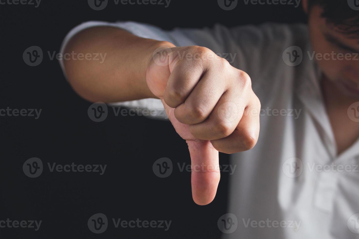 The man shows thumb down sign. Salary man or business man frowns. Unlike or bad concept. Close up shot with copy space. photo