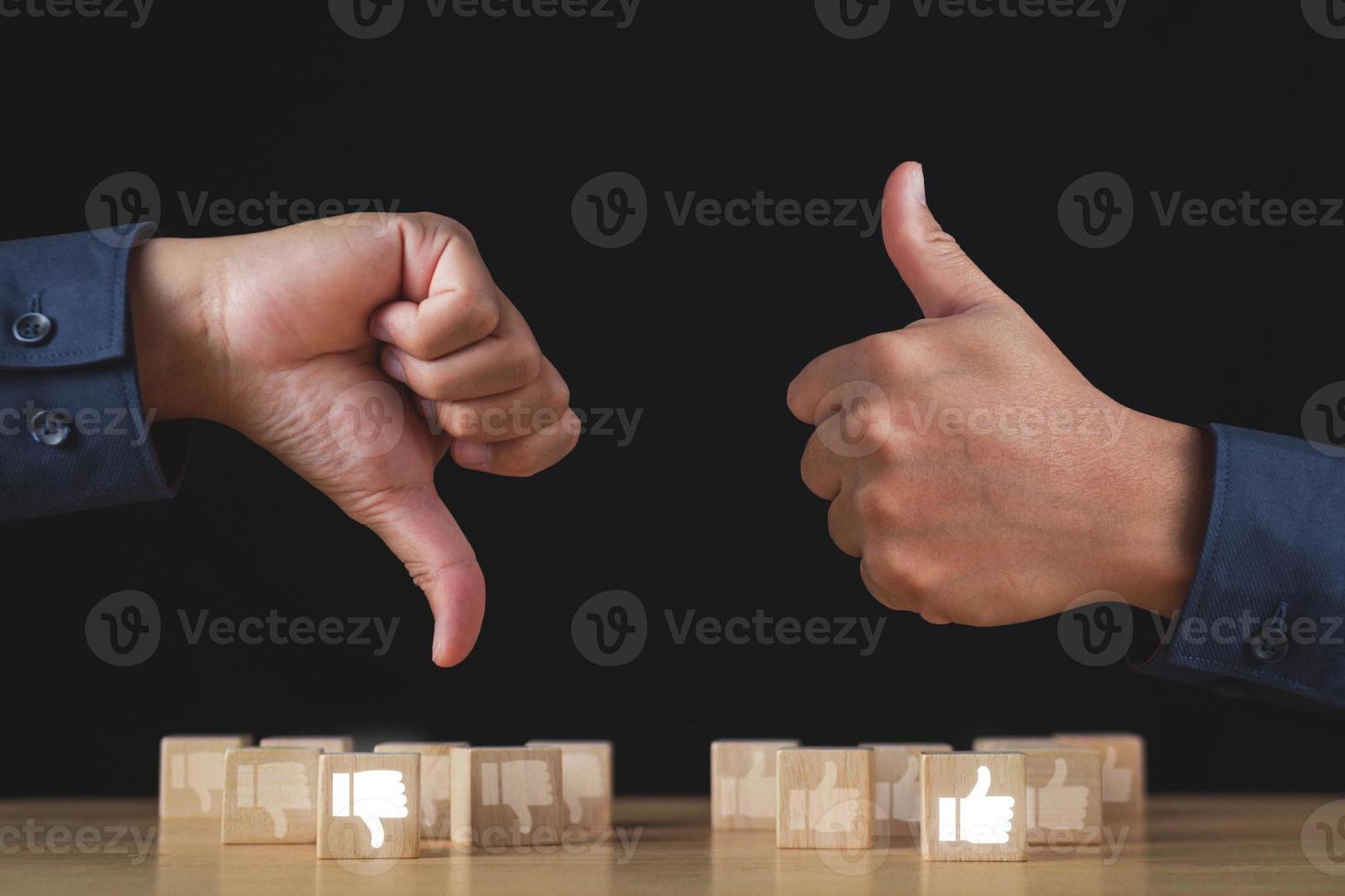 Sign of thumbs up and thumbs down to show the like and unlike feeling. Hands and wood blocks isolated on black background. Evaluation and satisfaction concept photo