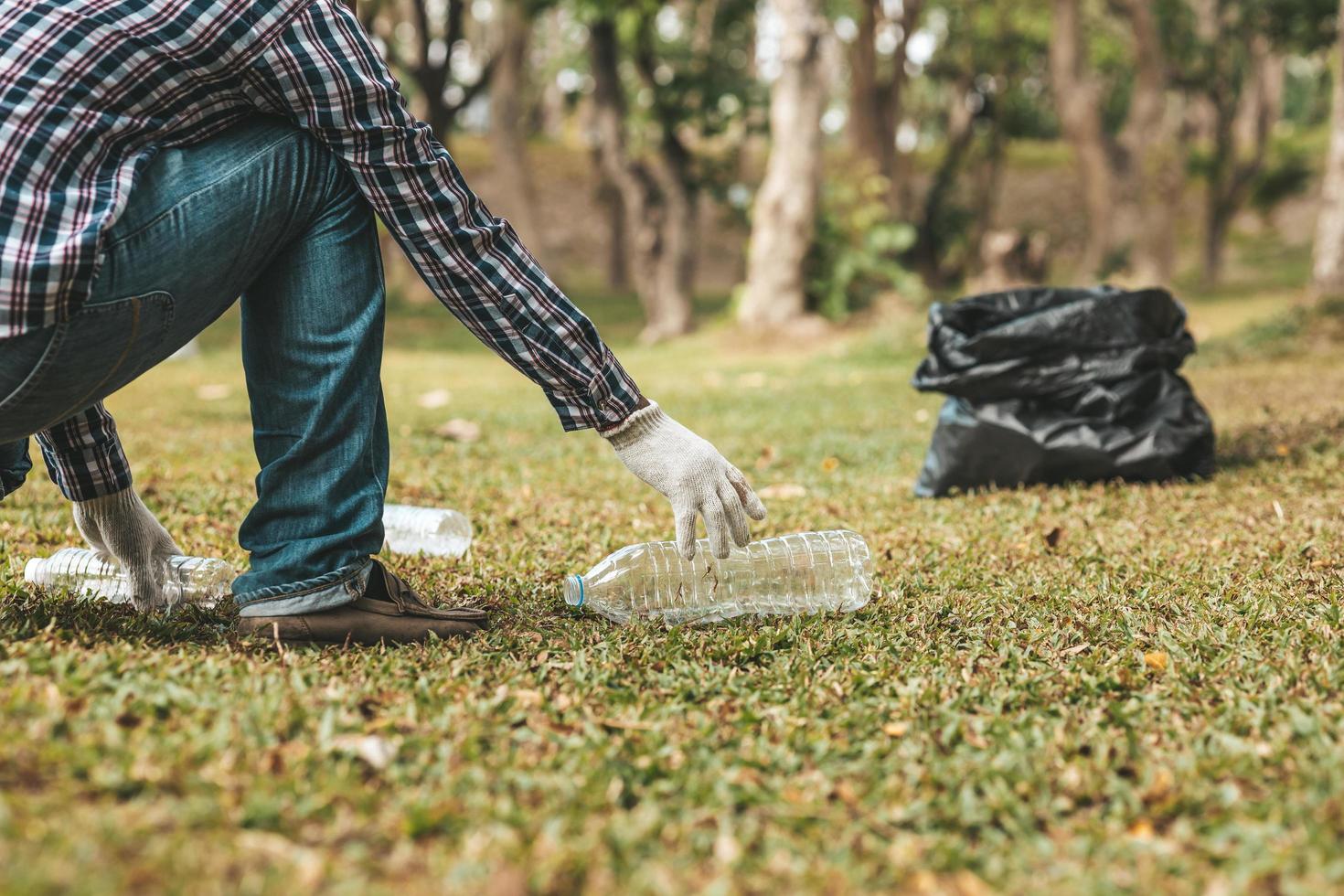 A man is picking up trash in a park, not throwing trash in the trash can ruin the beauty of the garden area and also cause global warming and harm animals. Concept of cleanliness in public areas. photo