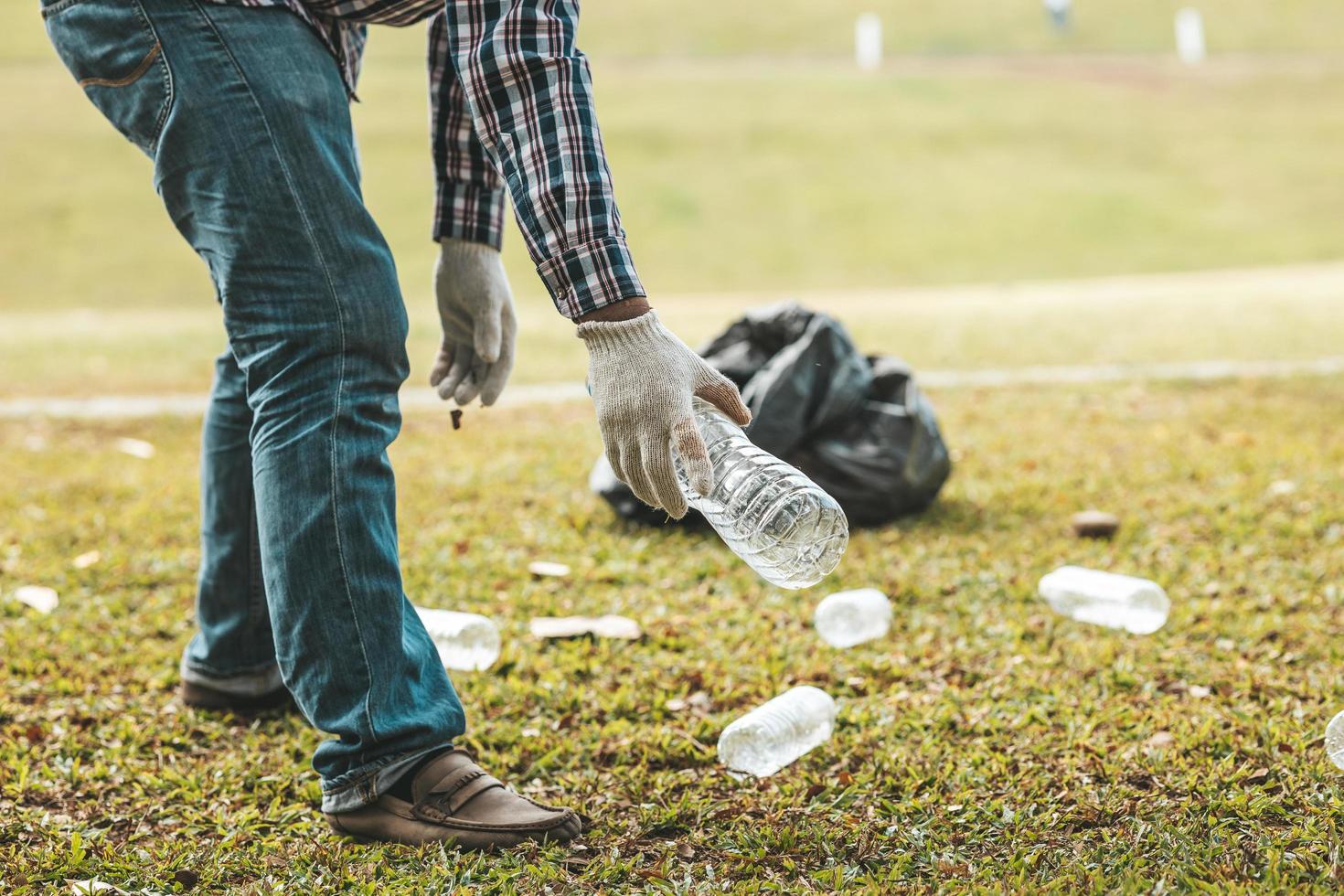 un hombre está recogiendo basura en un parque, no tirando basura en la basura puede arruinar la belleza del área del jardín y también causar el calentamiento global y dañar a los animales. concepto de limpieza en áreas públicas. foto