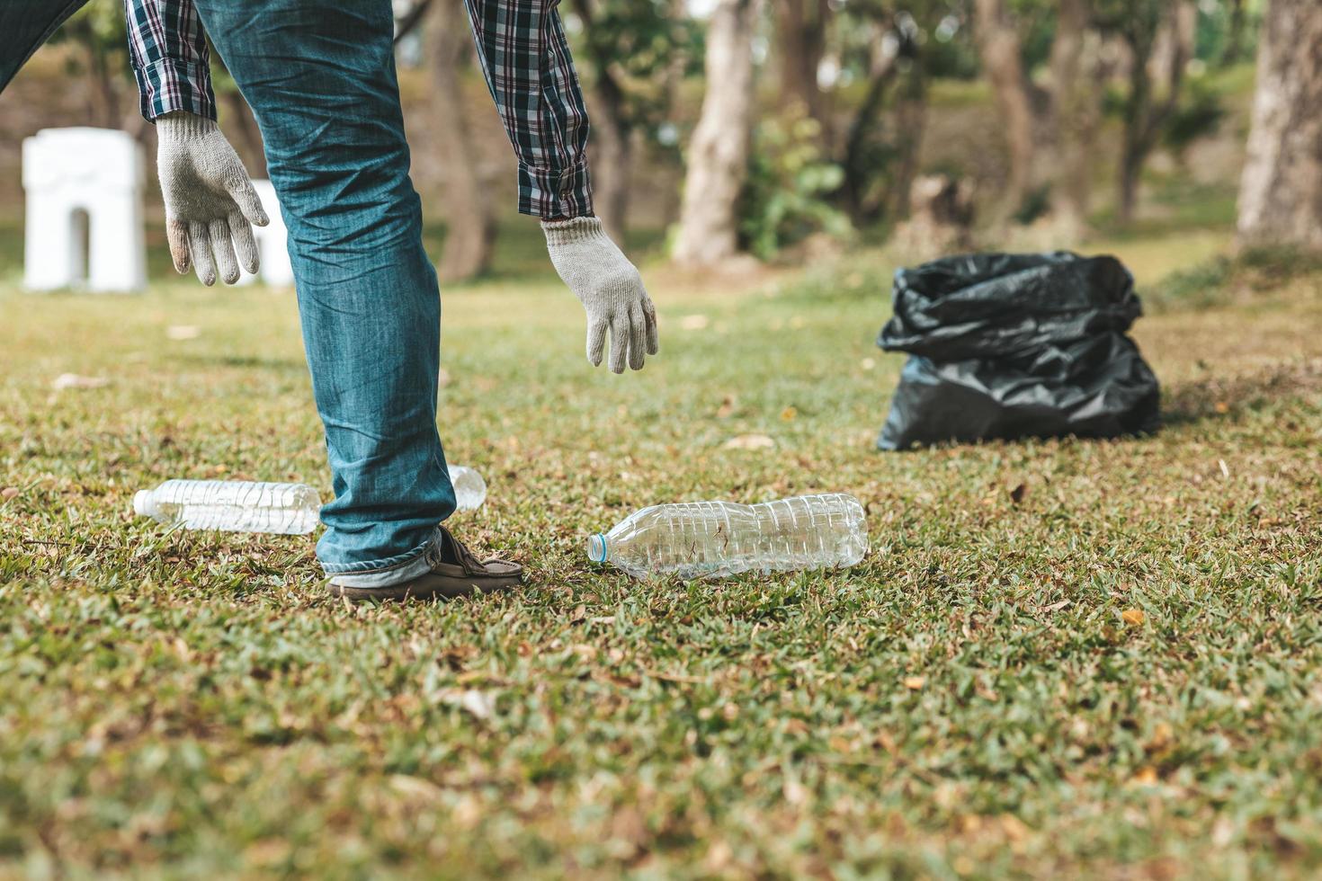 A man is picking up trash in a park, not throwing trash in the trash can ruin the beauty of the garden area and also cause global warming and harm animals. Concept of cleanliness in public areas. photo