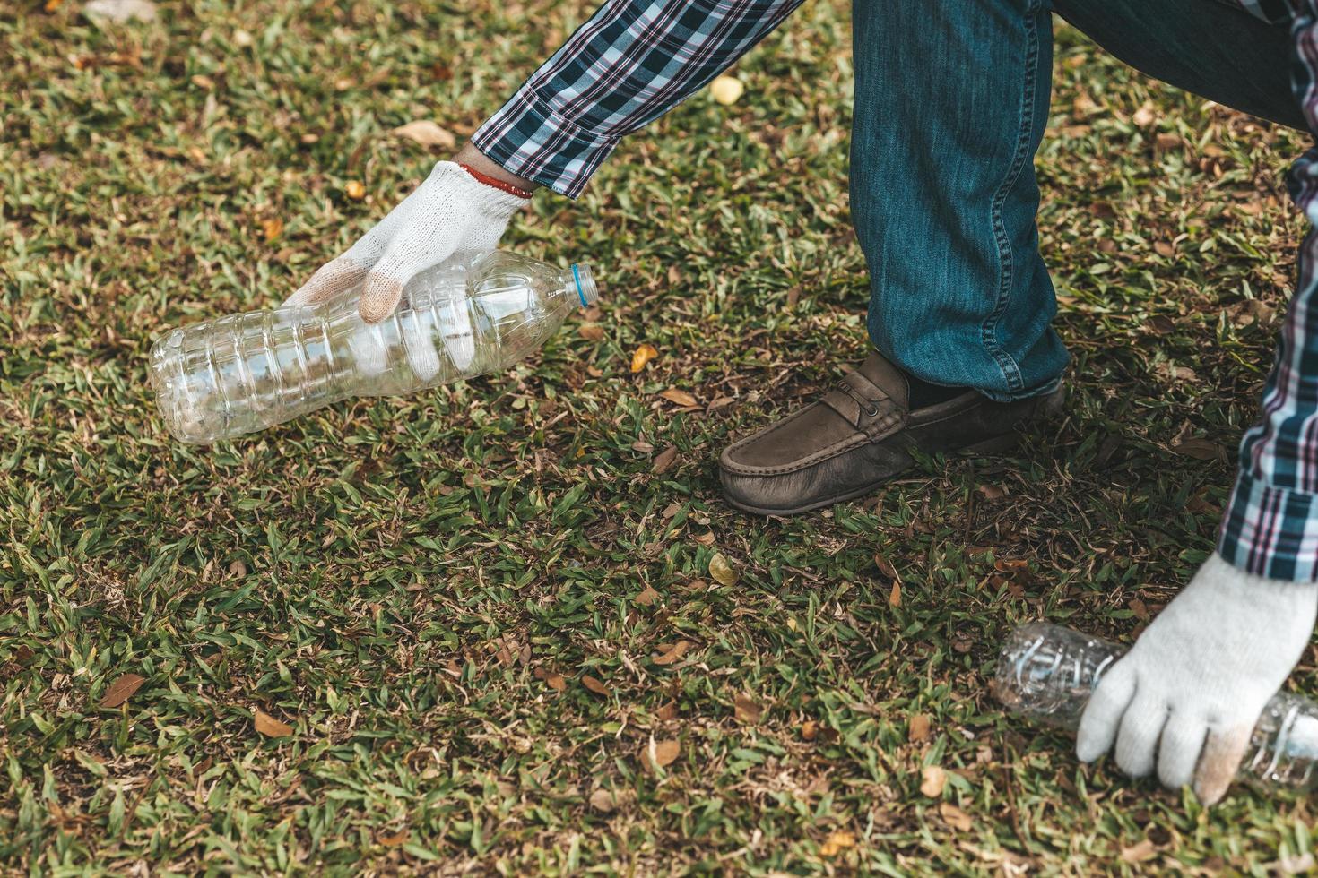 A man is picking up trash in a park, not throwing trash in the trash can ruin the beauty of the garden area and also cause global warming and harm animals. Concept of cleanliness in public areas. photo