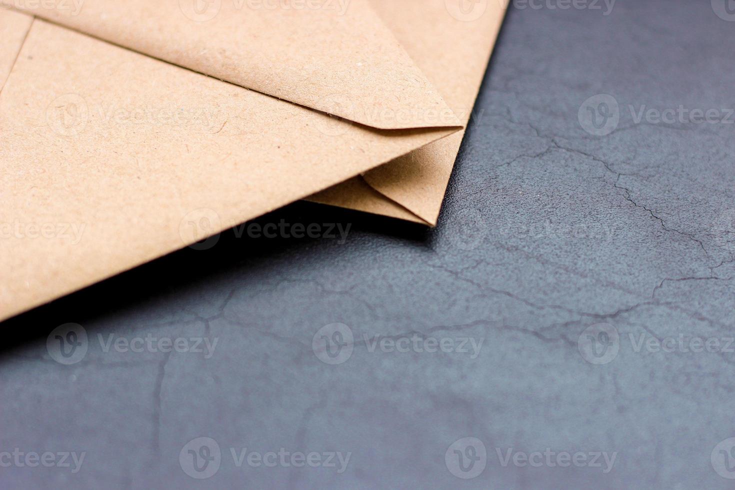 Corners of light brown kraft paper envelopes lying on dark textured background, horizontal photo. Empty space, objects in upper left corner, clean sheet photo
