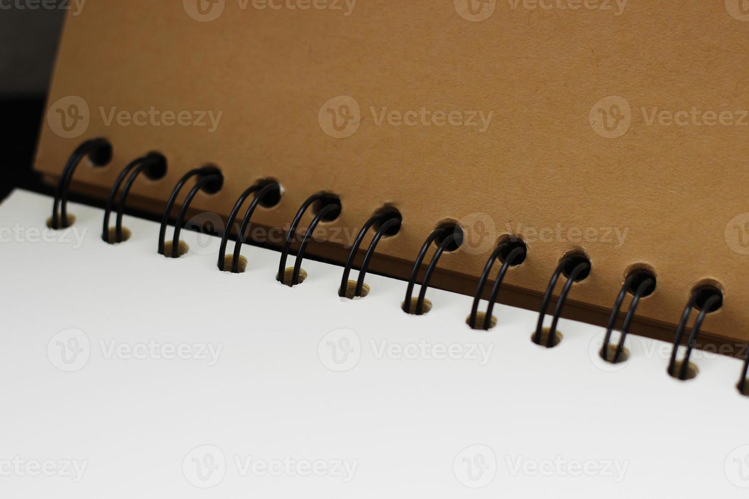 Black notepad spring connecting white and brown craft paper blank pages, closeup, horizontal photo. Open notepad, empty sheet space for text and design photo