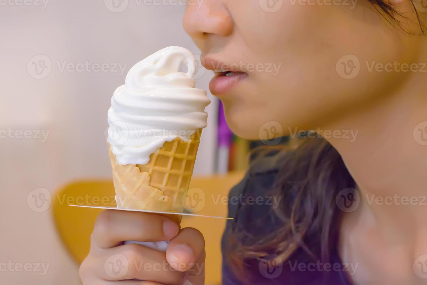 A girl eating ice cream cone white. photo