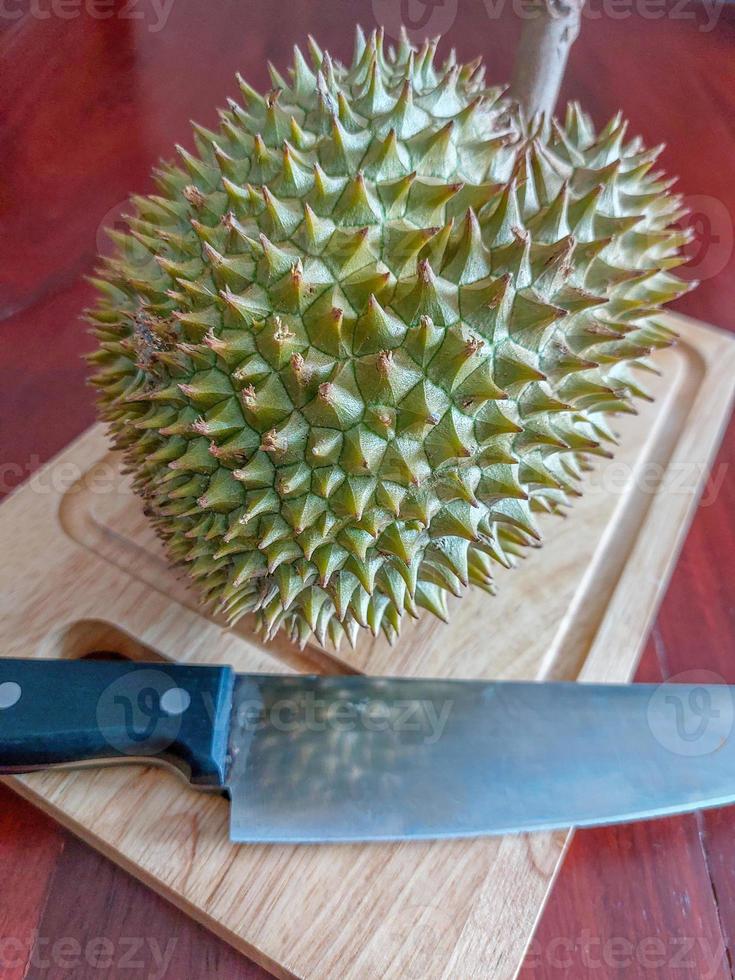 Green durian and knife on the wooden cutting board. photo