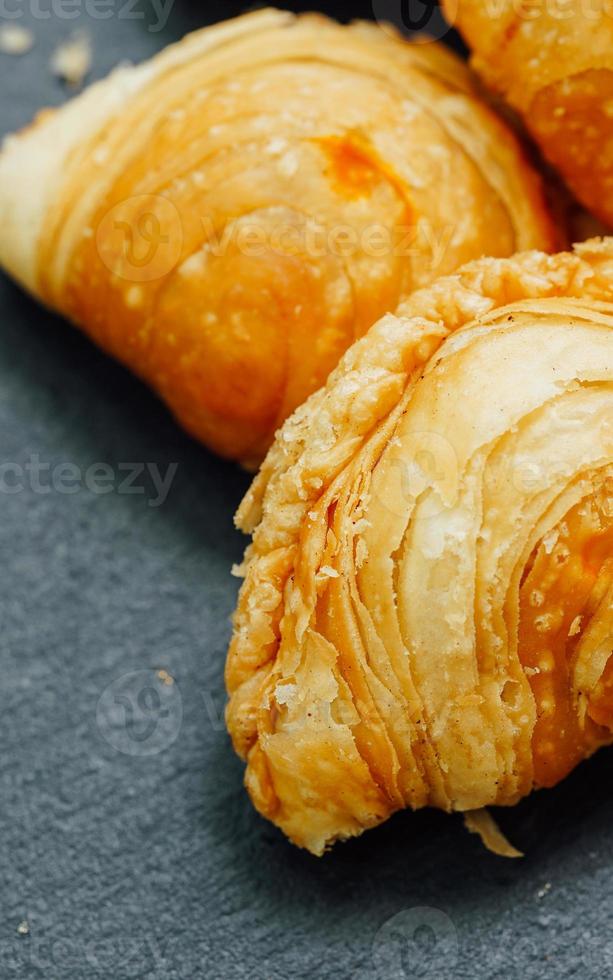 Curry puff pastry in a stone plate placed on a wooden table. photo