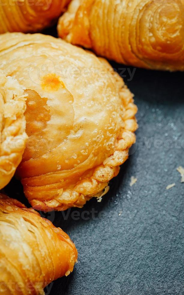 Curry puff pastry in a stone plate placed on a wooden table. photo