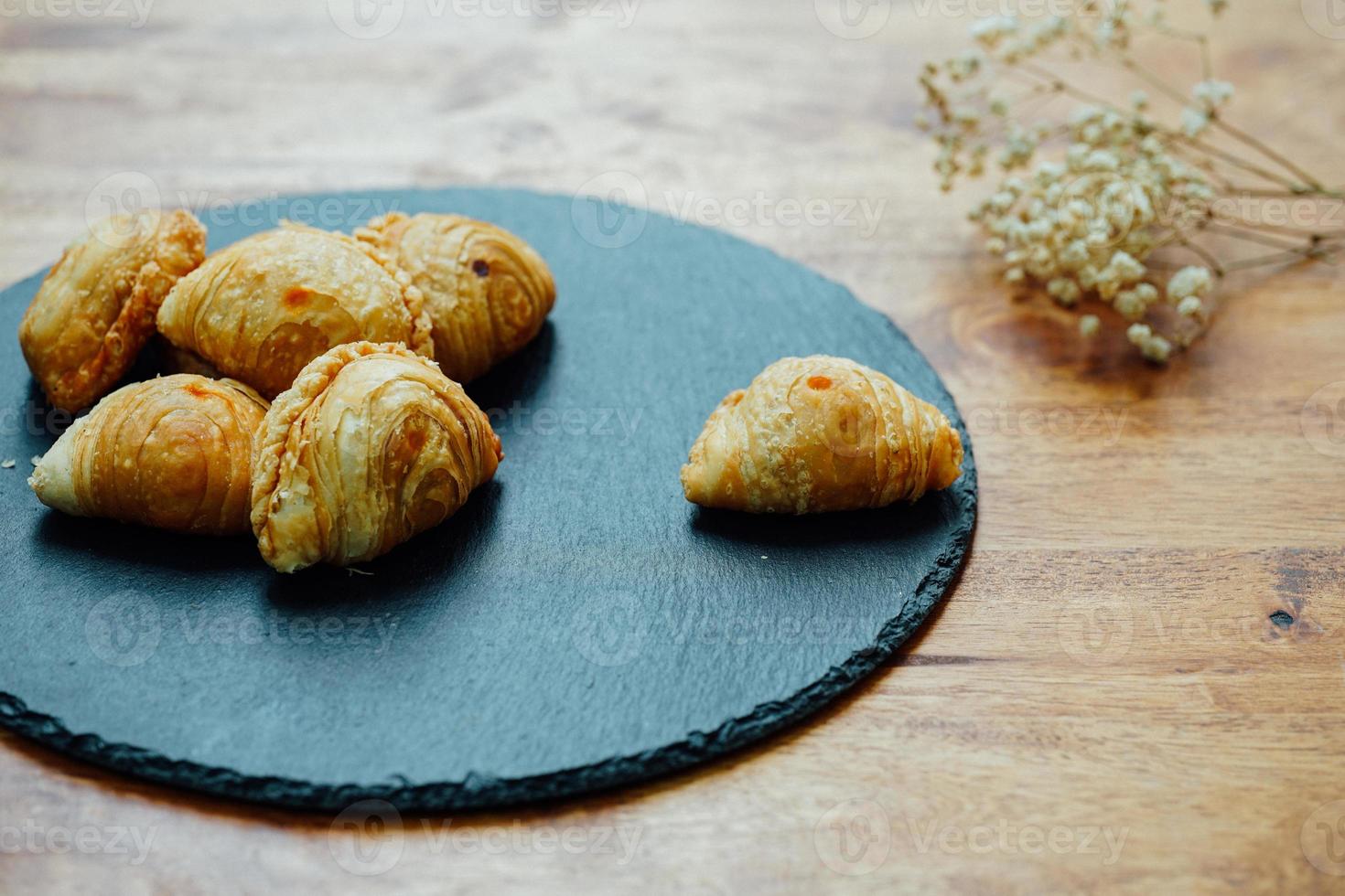Curry puff pastry in a stone plate placed on a wooden table. photo