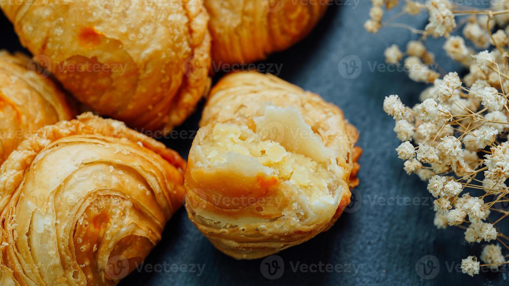 Curry puff pastry in a stone plate placed on a wooden table. photo