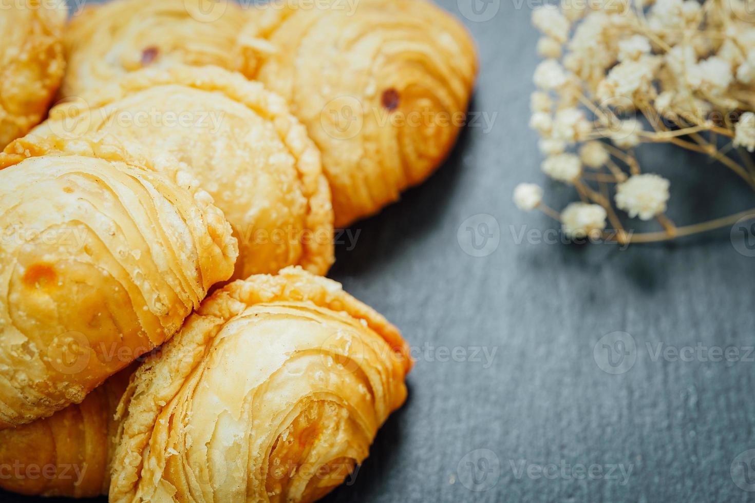 Curry puff pastry in a stone plate placed on a wooden table. photo