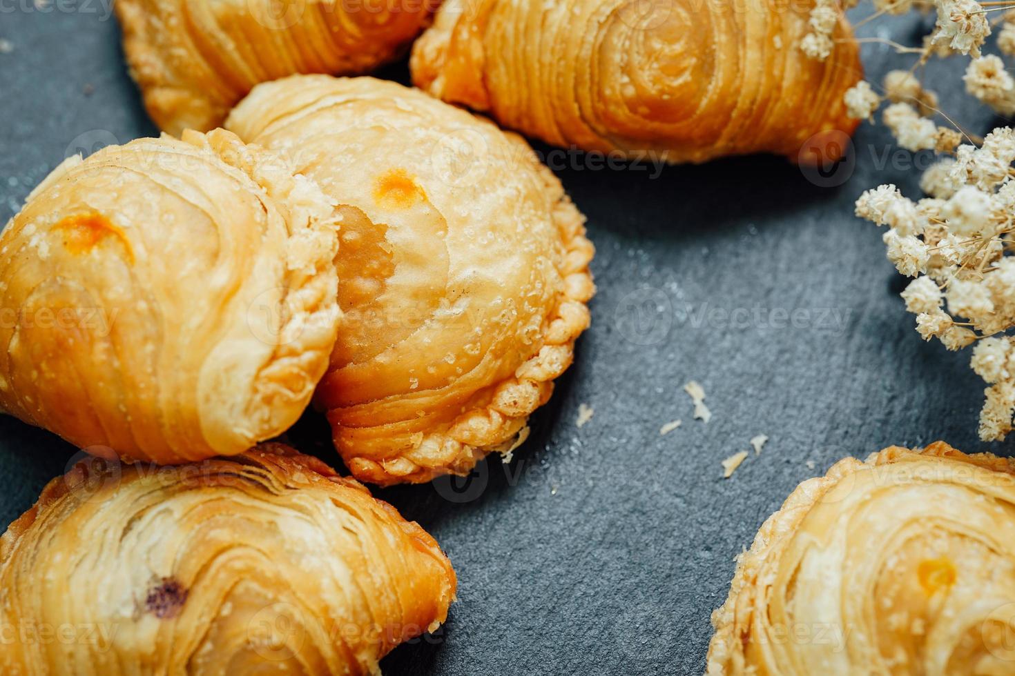 Curry puff pastry in a stone plate placed on a wooden table. photo