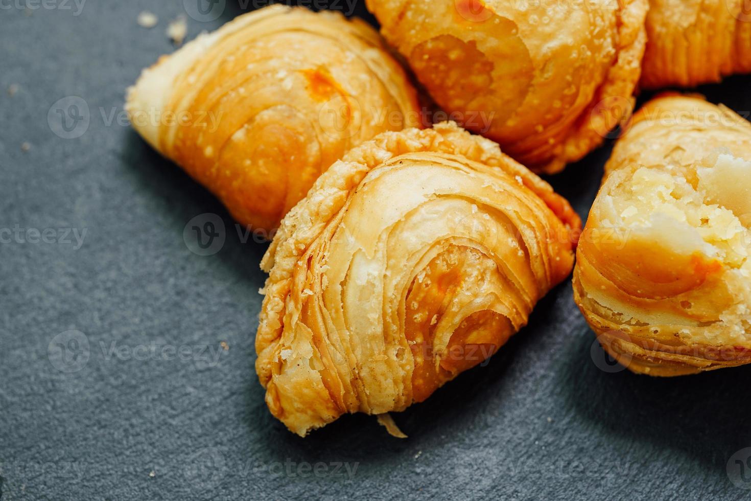 Curry puff pastry in a stone plate placed on a wooden table. photo