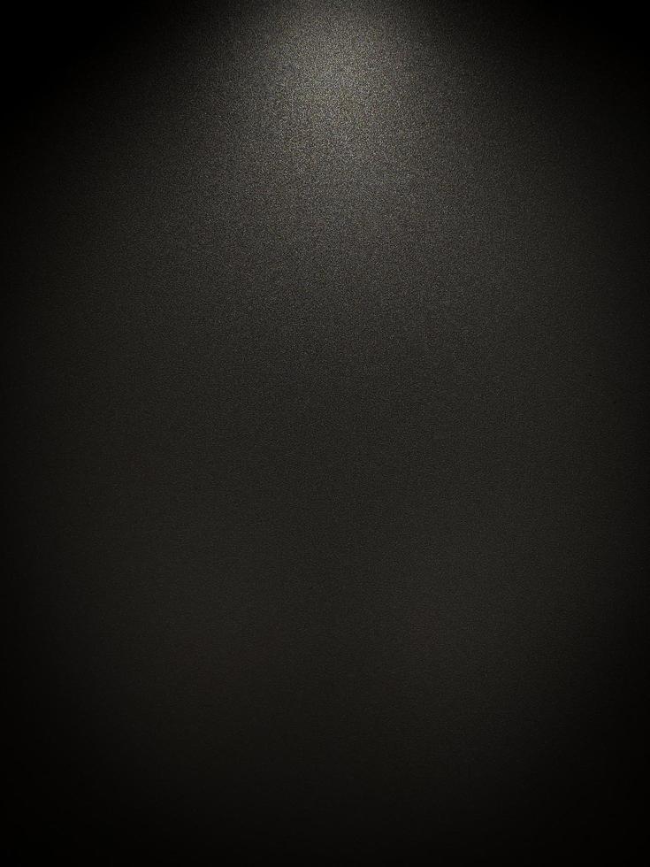 Abstract Grunge empty dark grey black wall with pattern texture grain material background with bright spotlight Rough illuminated surface shot from above. There's a vignette in the corner, copy space. photo