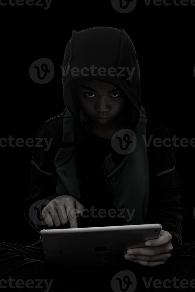 Hacker boy are hacking through the tablet on a black background. photo