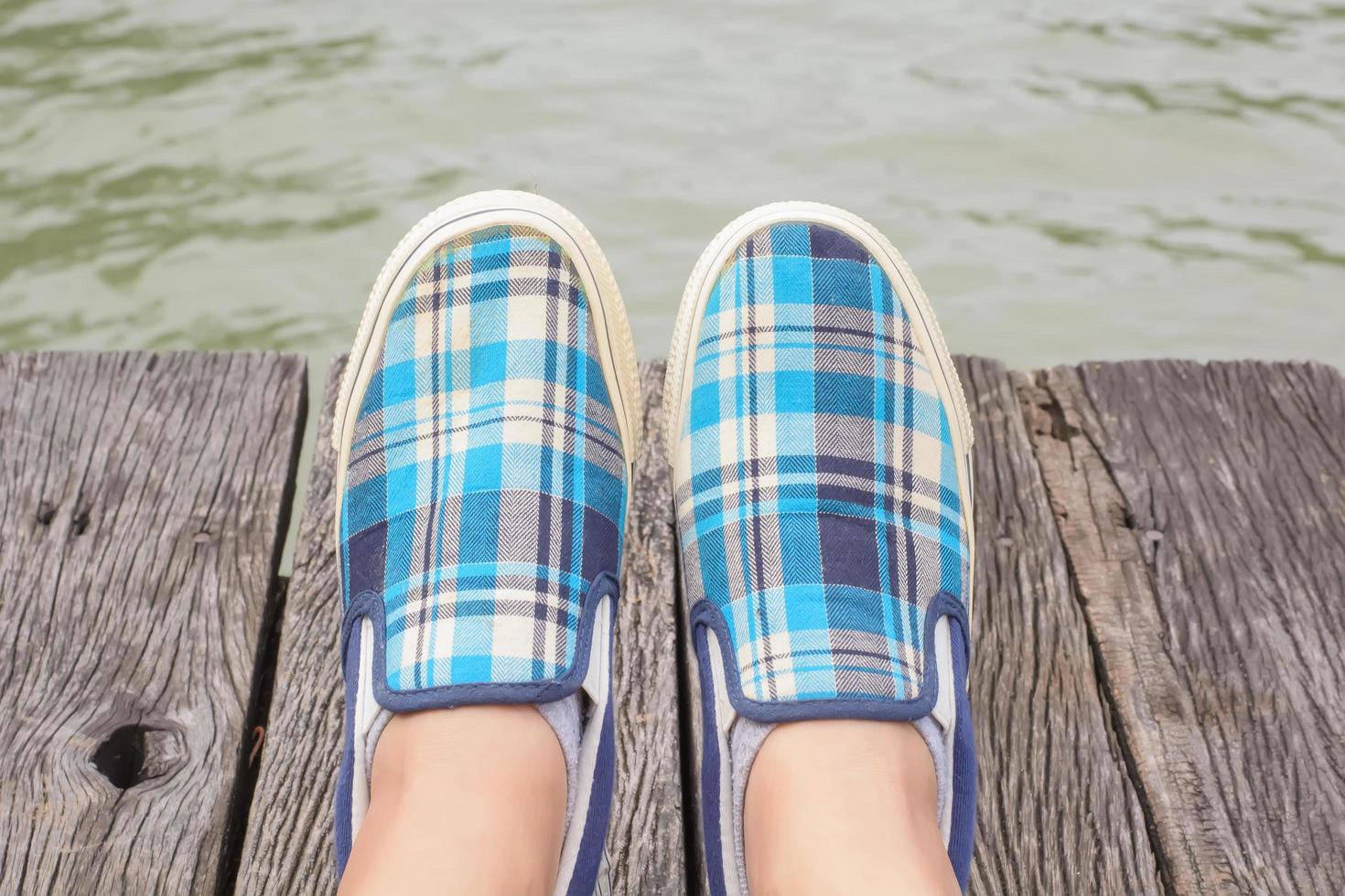 zapatillas de lona en los pies sobre el puente de madera foto