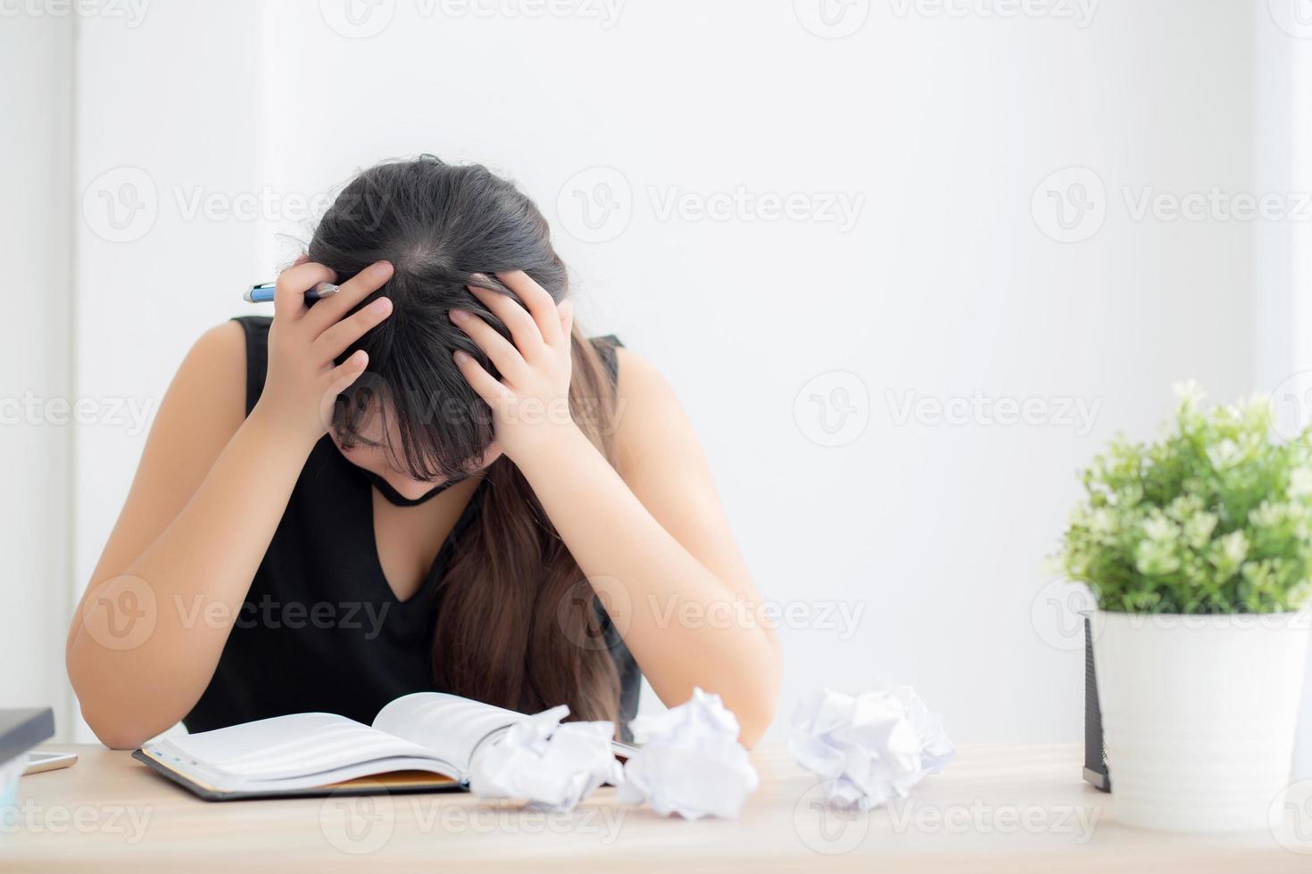 Beautiful asian woman tired and stressed with writing overworked at desk, girl with worried not idea with notebook and crumpled paper at office, freelance and business concept. photo