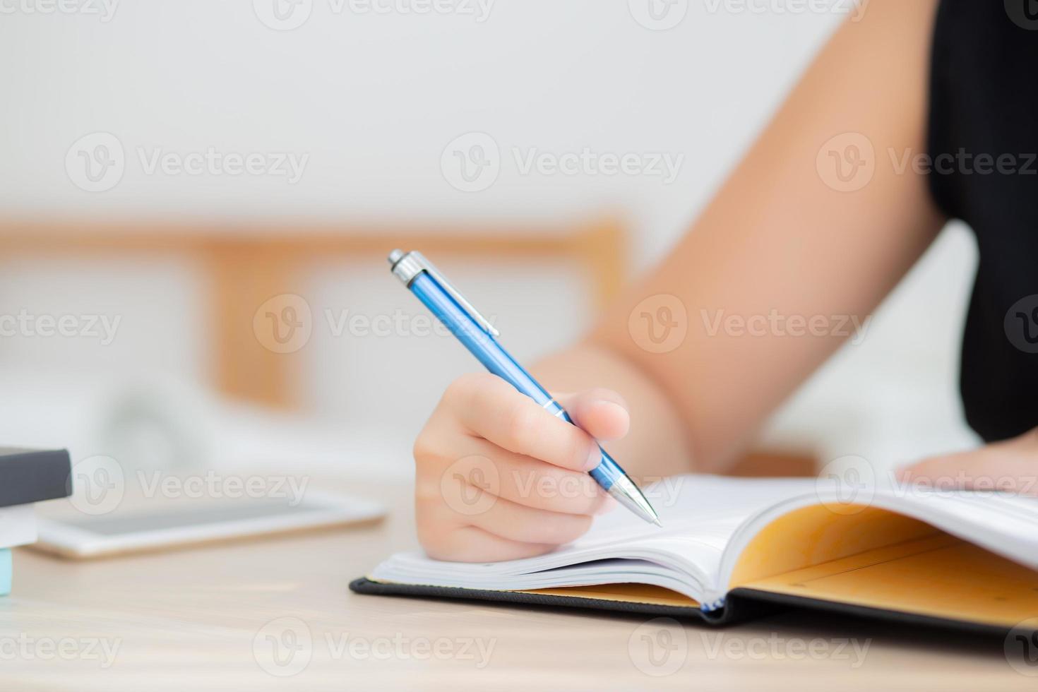 mujer asiática de primer plano sentada estudiando y aprendiendo a escribir cuaderno y diario en la mesa en la sala de estar en casa, tarea de niña, mujer escritora de negocios trabajando en la mesa, concepto de educación. foto