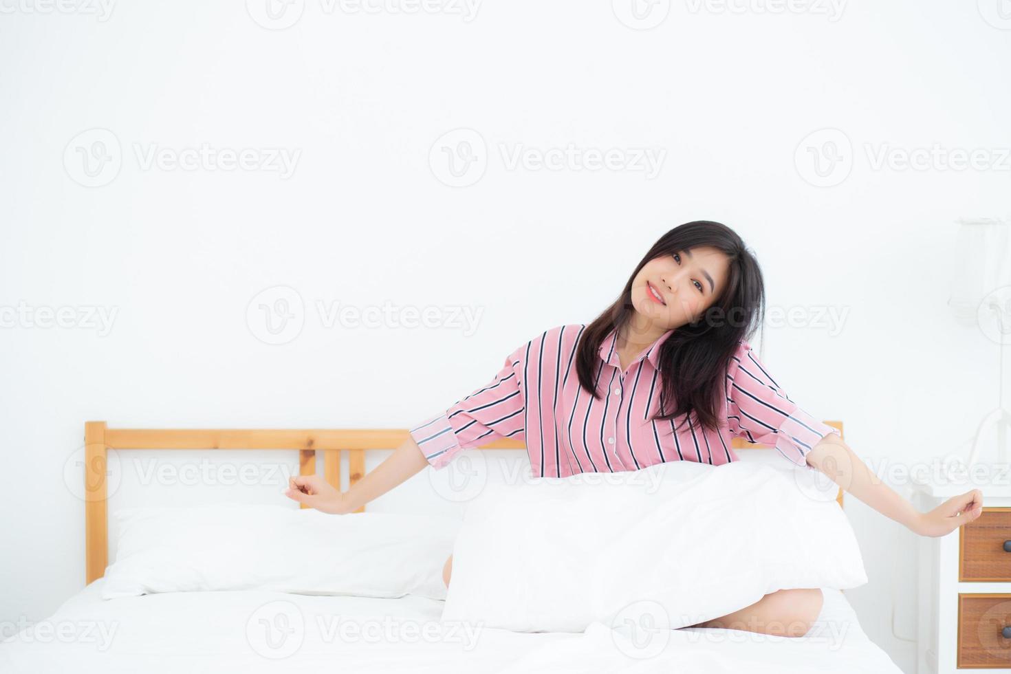 Beautiful of portrait young asian woman stretch and relax in bed after wake up morning at bedroom, new day and resting for wellness, lifestyle concept. photo