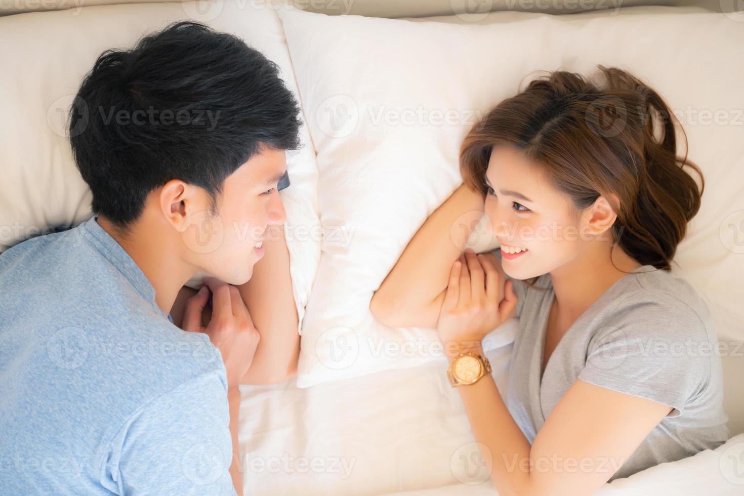 Beautiful young asian couple love looking eyes together on bed in the bedroom, man and woman with relationship, romantic concept. photo