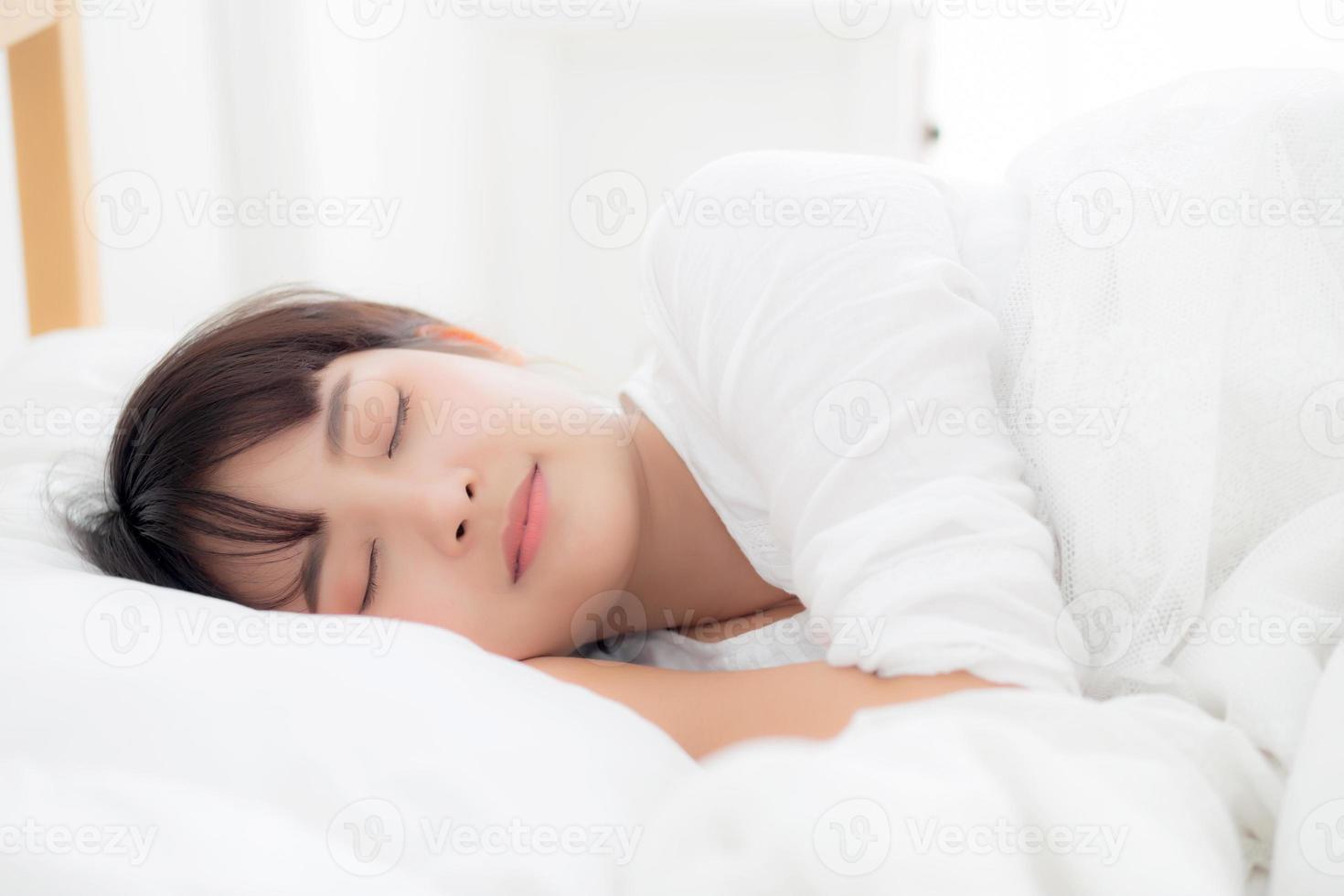 bella joven asiática durmiendo en la cama con la cabeza en la almohada cómoda y feliz. chica con relax por concepto de salud. foto