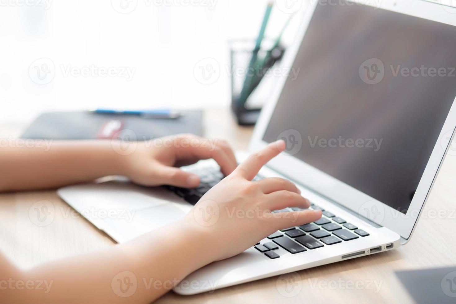Closeup freelance asian woman working and typing on laptop computer at desk office with professional, girl using notebook checking email or social network, business and lifestyle concept. photo
