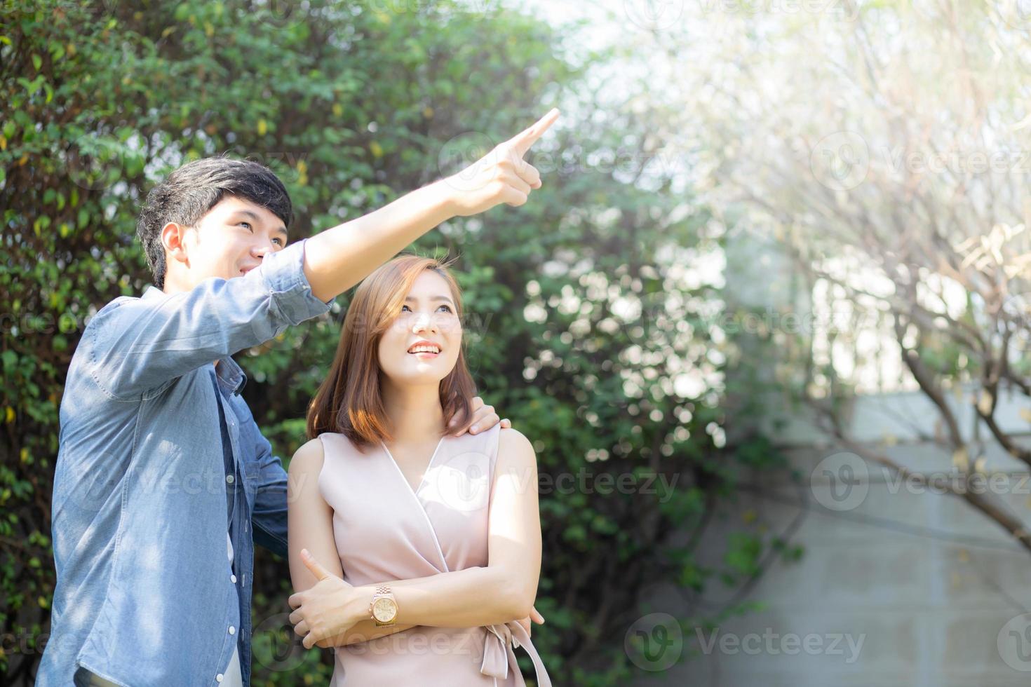 Beautiful portrait couple looking each others eyes and smiling with happy, young asian man and woman relation pointing something, husband and wife feeling and emotion, lovers and lifestyle concept. photo