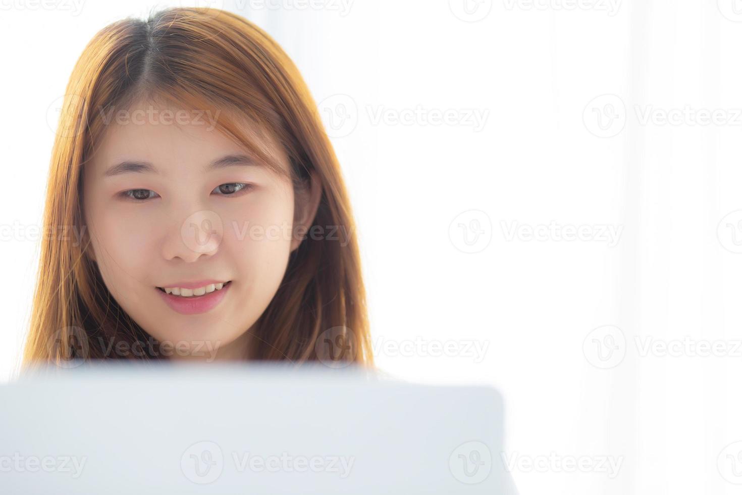 Portrait of beautiful asian young woman setting on bed using laptop computer at bedroom for leisure and relax, freelance with girl working notebook, communication and lifestyle concept. photo