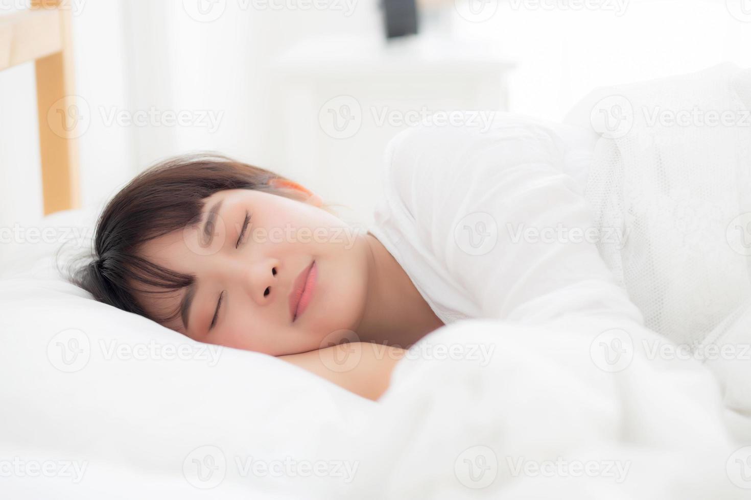 bella joven asiática durmiendo en la cama con la cabeza en la almohada cómoda y feliz. chica con relax por concepto de salud. foto