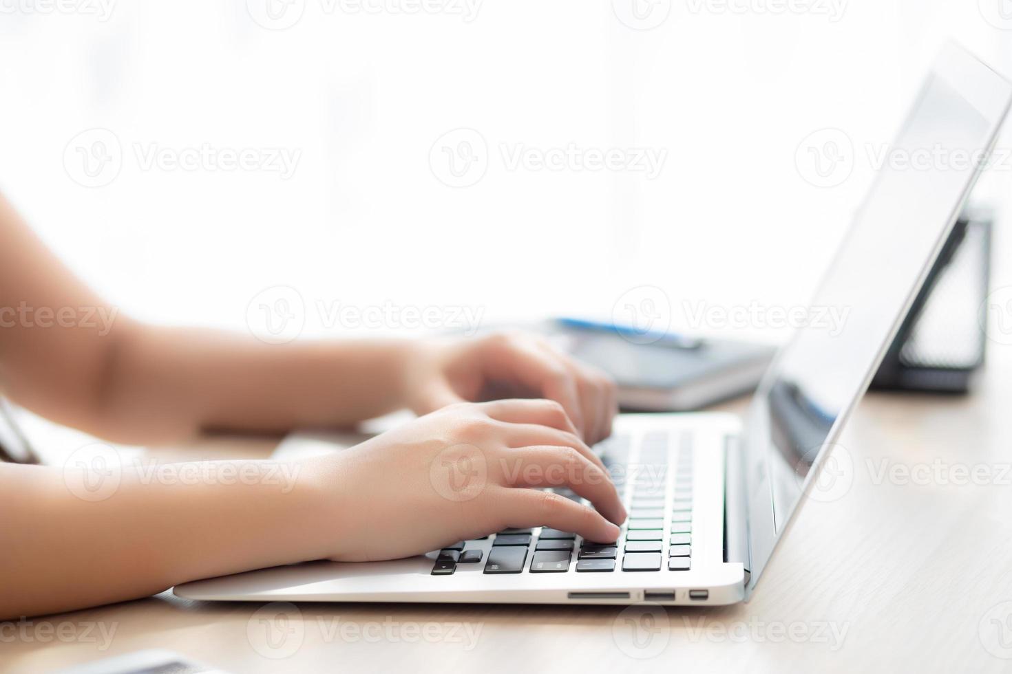 Closeup freelance asian woman working and typing on laptop computer at desk office with professional, girl using notebook checking email or social network, business and lifestyle concept. photo