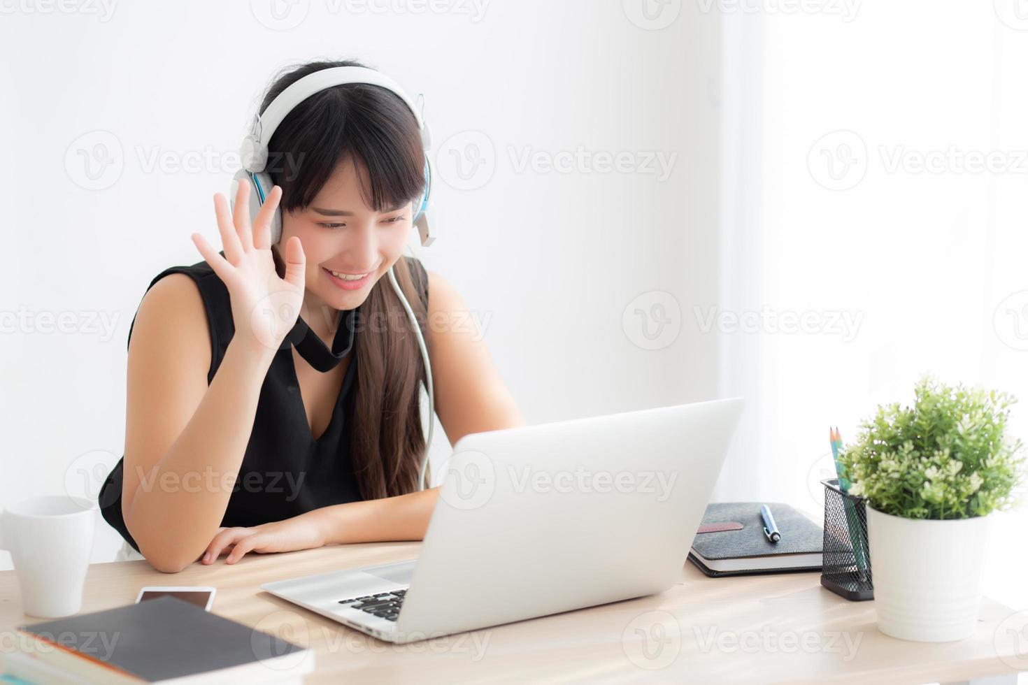 Beautiful young asian woman wear headphone smiling say hello using chat video call on laptop computer, girl relax enjoy listening music online, education learning, communication and lifestyle concept. photo