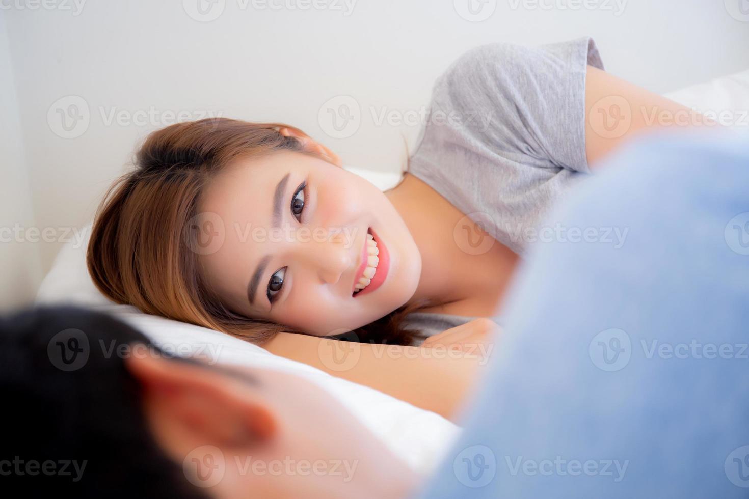 Beautiful young asian woman looking man, asia couple happy and smiling lying romantic love together in the bedroom, husband and wife relax and honeymoon in bedtime. photo