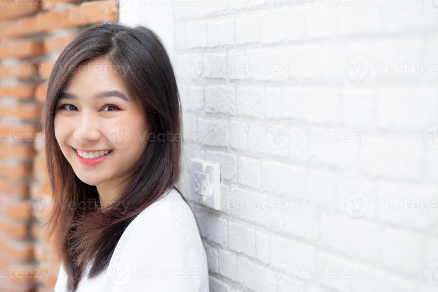 retrato de la hermosa joven mujer asiática felicidad de pie sobre fondo de ladrillo de pared de grunge de textura de cemento gris, mujer de negocios es una sonrisa en concreto, concepto de gente de negocios. foto