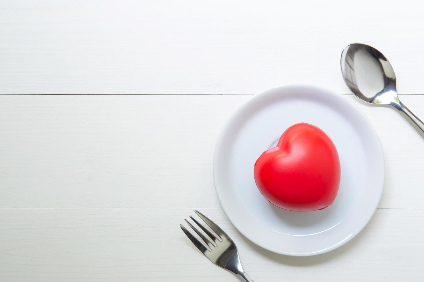 Red Heart with love and dish and spoon and fork on wooden background, 14 February Valentine day, on grunge white wood, celebration and holiday concept, top view. photo