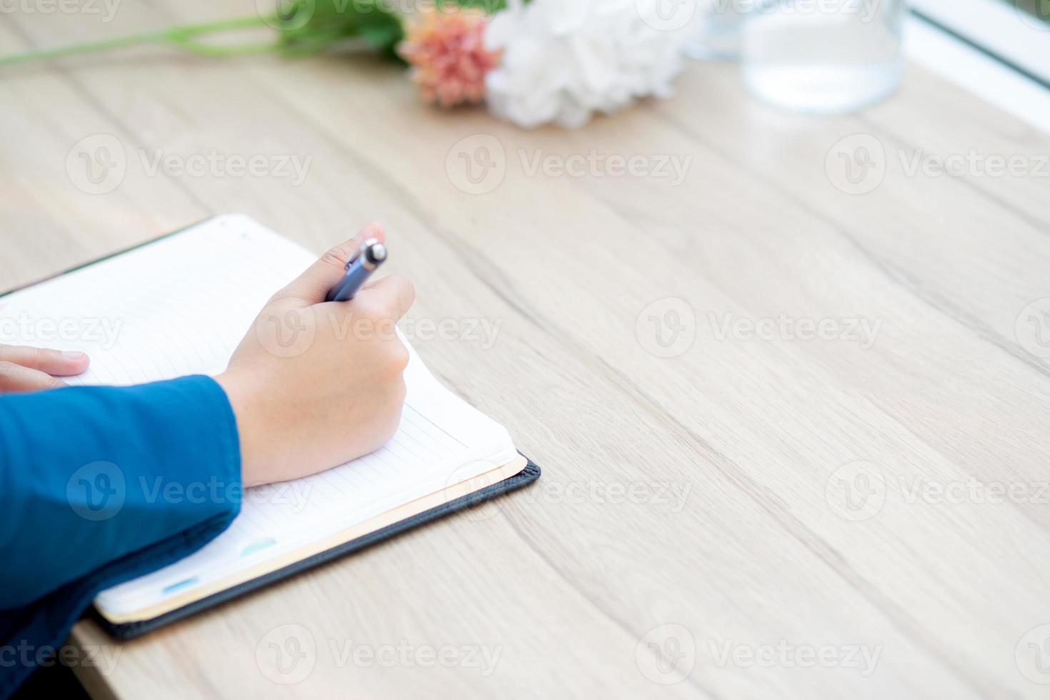 Closeup hand asian woman sitting study and learning writing notebook and diary on table in at cafe shop, girl homework, business writer female working on table, education concept. photo