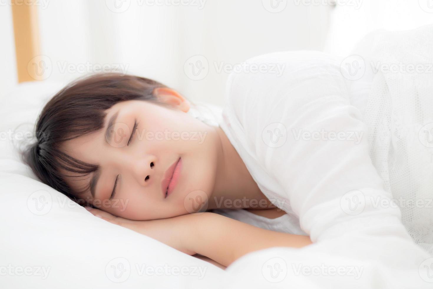 Beautiful asian young woman sleeping lying in bed with head on pillow comfortable and happy. girl with relax for health concept. photo