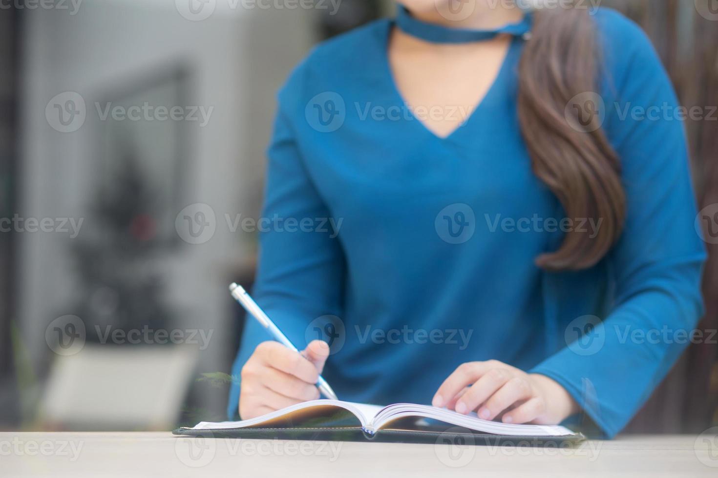Closeup hand asian woman sitting study and learning writing notebook and diary on table in at cafe shop, girl homework, business writer female working on table, education concept. photo