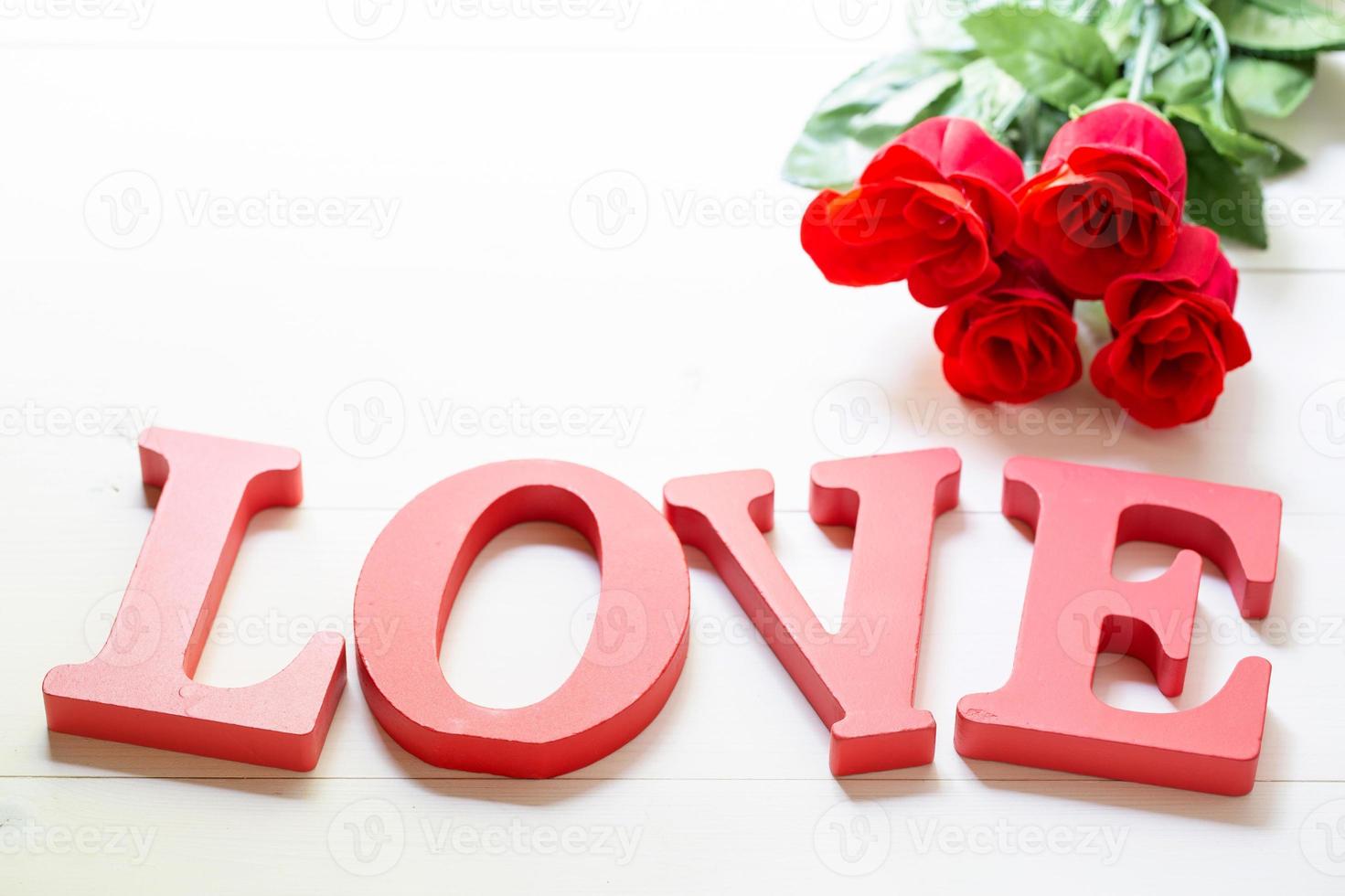 Present gift with red rose flower and word love on wooden table, 14 February with romantic, valentine holiday concept. photo