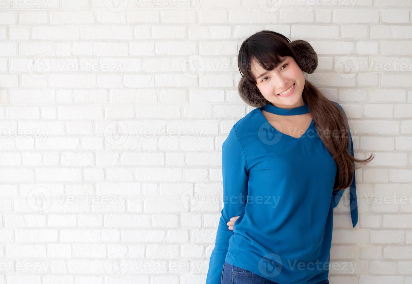 retrato de una hermosa joven asiática disfrutando y feliz de pie sobre un fondo de ladrillo de pared gris con textura de cemento, la chica es una sonriente y alegre sobre hormigón. foto