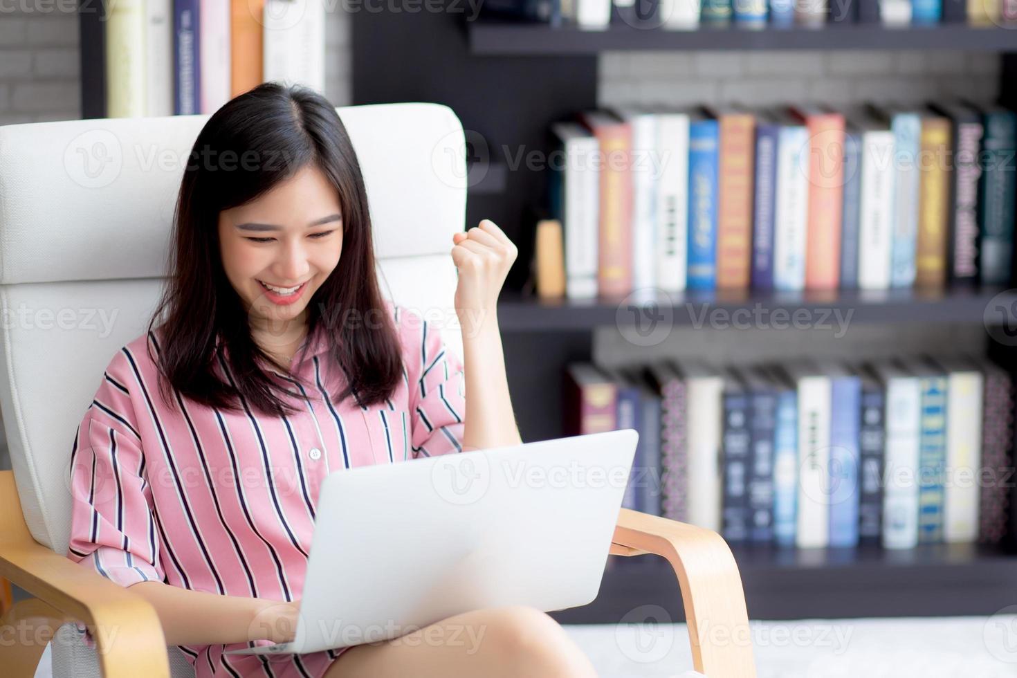 Beautiful of portrait asian young woman excited and glad of success with laptop on chair, girl working living room at home, career freelance business concept. photo