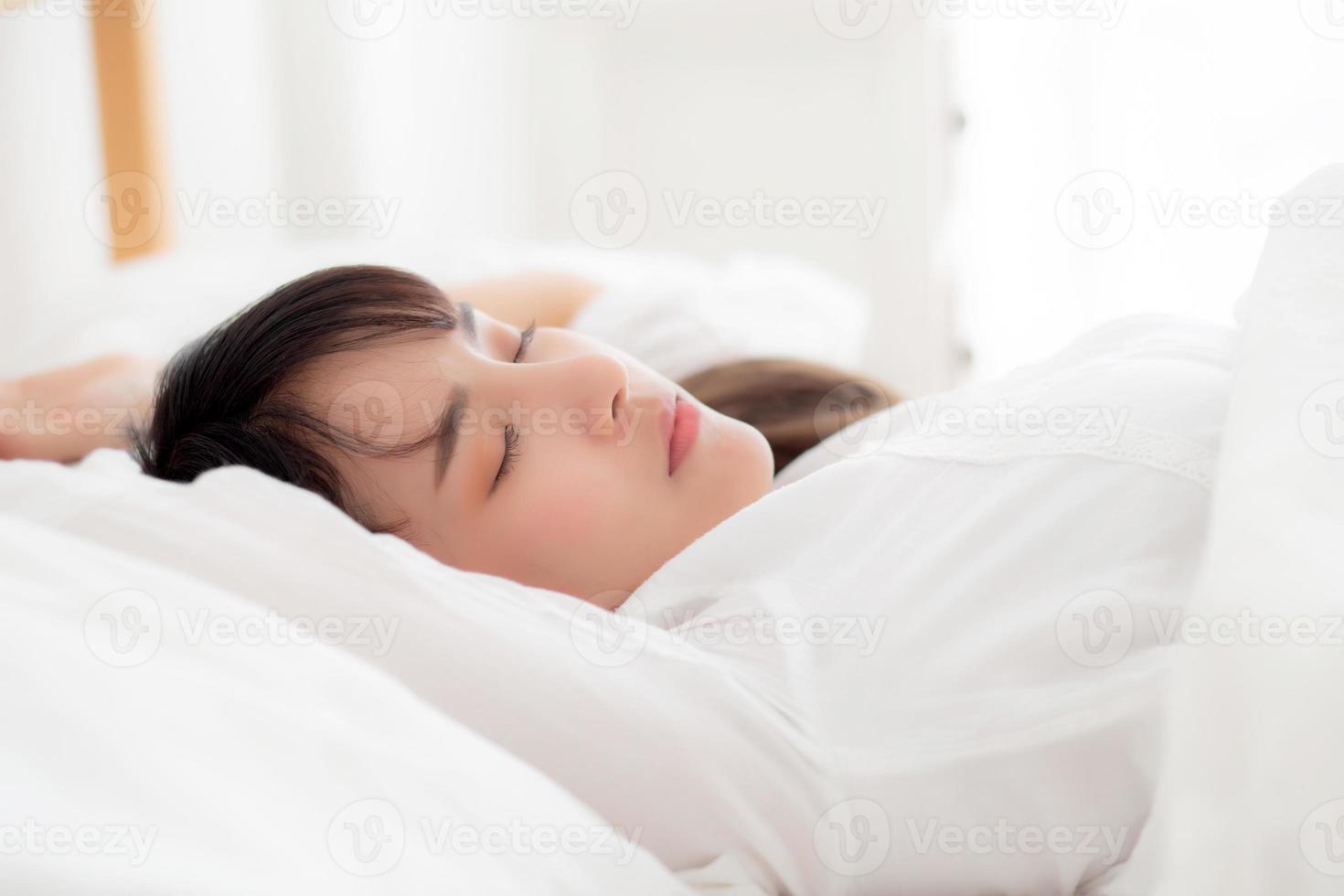 Beautiful asian young woman sleeping lying in bed with head on pillow comfortable and happy. girl with relax for health concept. photo