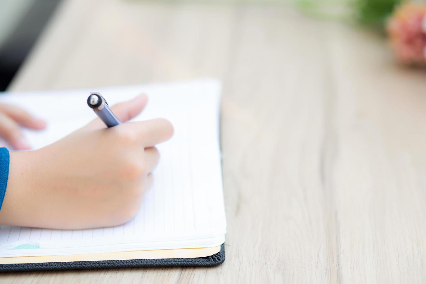 Closeup hand asian woman sitting study and learning writing notebook and diary on table in at cafe shop, girl homework, business writer female working on table, education concept. photo